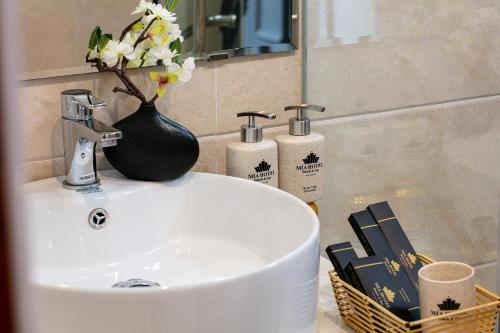 a bathroom sink with a vase with flowers on it at MIA HOTEL in Hanoi