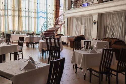 a dining room with tables and chairs with white tablecloths at Optima Collection Aurora Kryvyi Rih in Kryvyi Rih