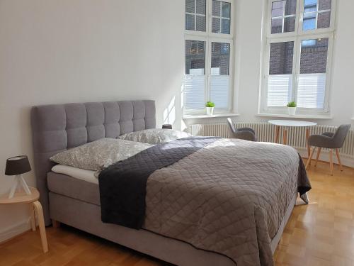 ein Schlafzimmer mit einem Bett und zwei Fenstern in der Unterkunft Apartment Villa Kronenberg in Bochum