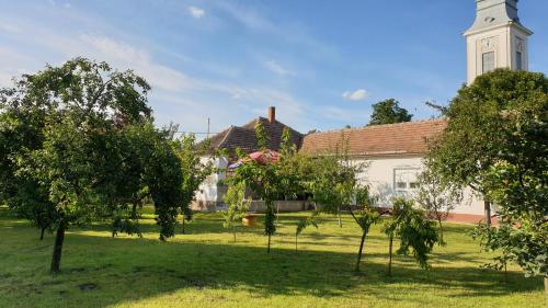 a church with trees in front of a grass field at Mélyvíz II Apartman in Poroszló