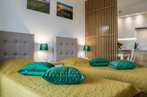 2 łóżka z zielonymi poduszkami w sypialni w obiekcie Apartament Podlaskidron w mieście Białystok