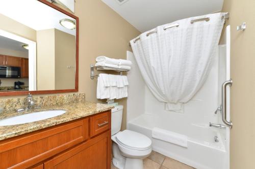 a bathroom with a sink and a toilet and a mirror at Candlewood Suites Chambersburg, an IHG Hotel in Chambersburg