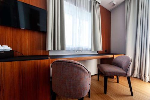 a room with a desk with two chairs and a television at Hotel Ocelle Thermae&Spa (Adults Only) in Sirmione