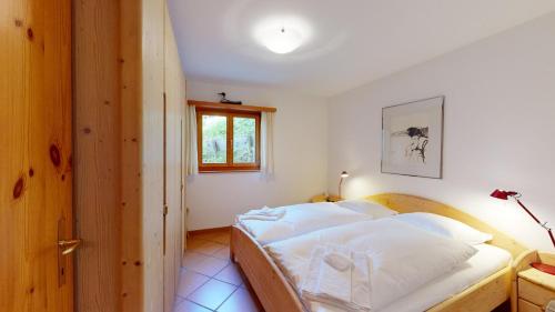 um quarto com uma cama com lençóis brancos e uma janela em Abitaziun Murinella - Pontresina em Pontresina