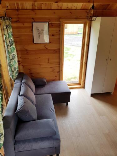 a living room with a couch and a large window at Leśna Osada przy Suntago Park in Krzyżówka