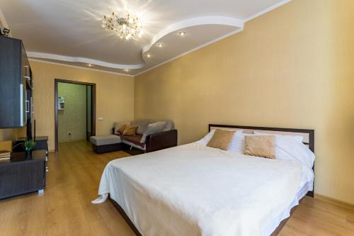 1 dormitorio con 1 cama blanca grande y 1 sofá en EtazhiDaily - ZHK Bazhovsky, en Yekaterinburg