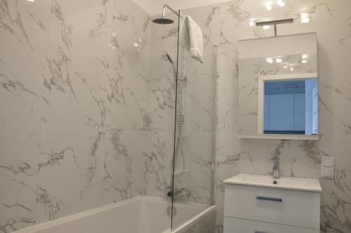 a bathroom with a shower and a tub and a sink at Prudentia Apartments Lifetown in Warsaw