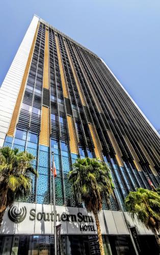 a tall building with palm trees in front of it at Southern Sun Abu Dhabi in Abu Dhabi