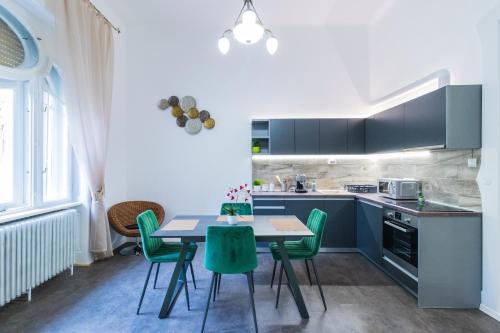 eine Küche mit einem Tisch und grünen Stühlen in der Unterkunft Gróf palace Apartman in Szeged