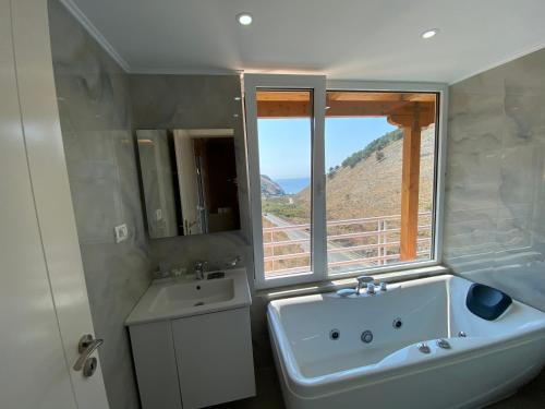 baño con bañera, lavabo y ventana en Karos Hotel Llaman, en Himare