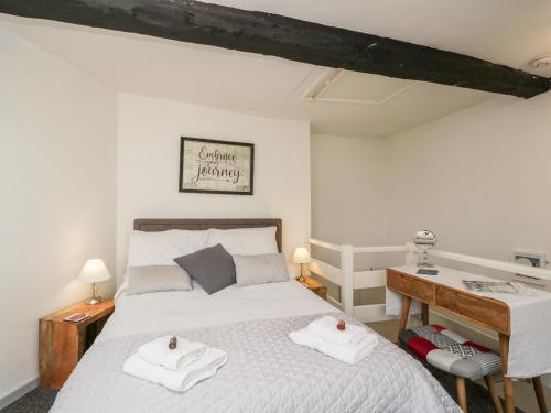 een slaapkamer met een bed en een bureau met handdoeken bij Cobblers Cottage in Worcester