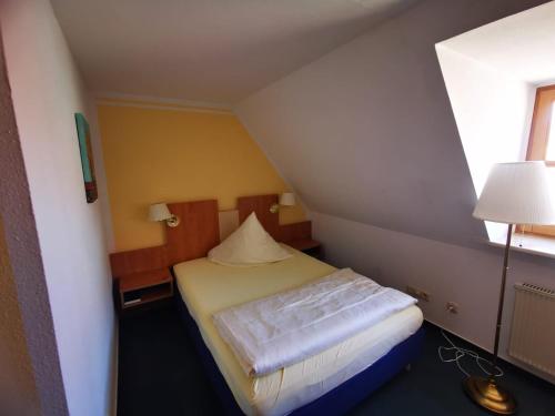 a small room with a bed and a lamp at Hotel Thüringer Hof in Sondershausen