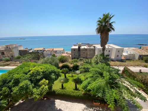 a view of a resort with a palm tree and the ocean at Casa vacanza lido in Sciacca