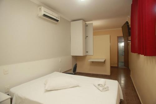 1 dormitorio con cama blanca y cortina roja en Campos Gerais Hotel, en Belo Horizonte