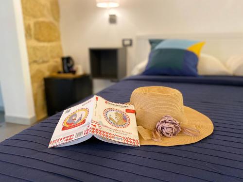 un cappello di paglia poggiato sopra un letto di B&B Donna Teresa a Agrigento
