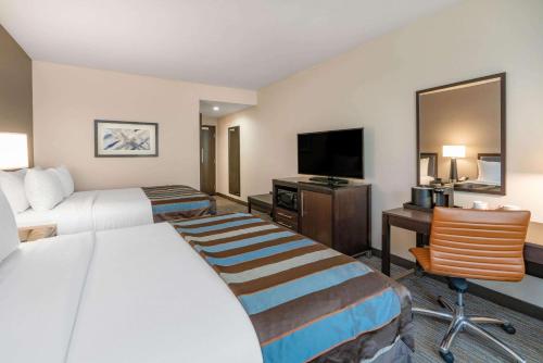 a hotel room with two beds and a flat screen tv at Wingate by Wyndham Moab in Moab