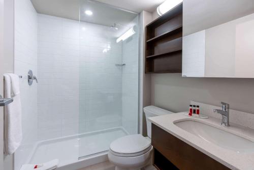 a white bathroom with a toilet and a sink at Microtel Inn & Suites by Wyndham Portage La Prairie in Portage La Prairie