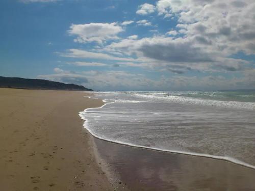 a sandy beach with waves coming in on the shore at ATICO DUPLEX APARTAMENTO ATLANTERRA PLAYA, ZAHARA DE LOS ATUNES in Zahara de los Atunes