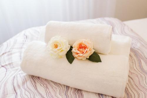 two flowers on a rolled up towel on a bed at Os Fragosinhos in Funchal