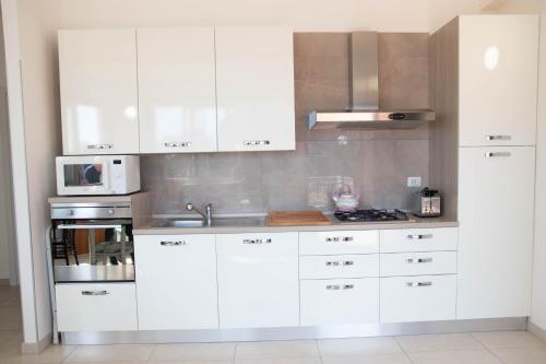 a kitchen with white cabinets and a microwave at Taormina Isola bella suite in Taormina