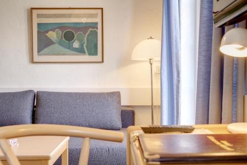 a living room with a blue couch and a table at Hotel Siemsens Gaard in Svaneke