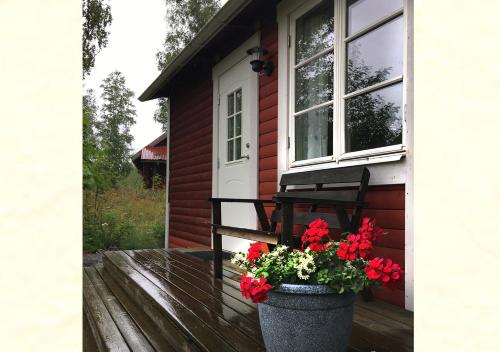 a porch of a house with a window and red flowers at Lillstugan Elofstorp in Kristinehamn