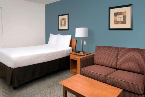 Habitación de hotel con cama y sofá en WoodSpring Suites Gainesville I-75, en Gainesville