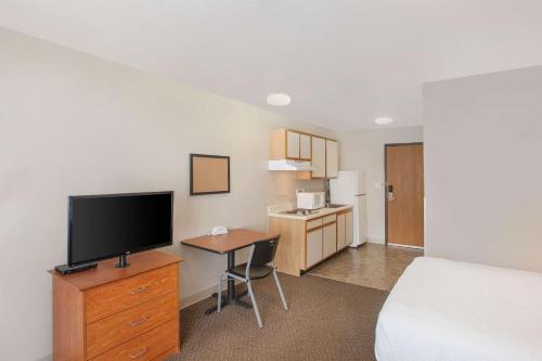 Habitación de hotel con cama y escritorio con TV. en WoodSpring Suites Jacksonville Beach Blvd, en Jacksonville