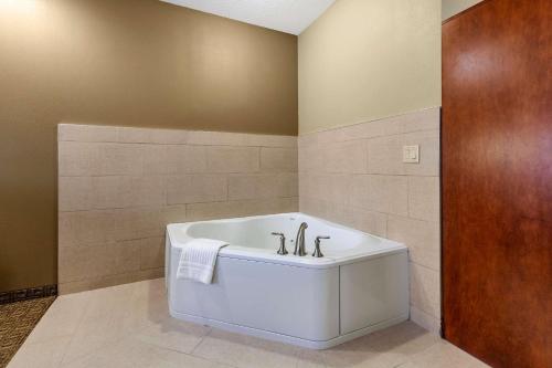 ein Bad mit einer weißen Badewanne in einem Zimmer in der Unterkunft Comfort Suites in Marquette