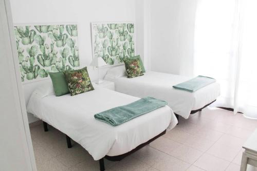 three beds in a room with white walls at VV Canteras Oasis "by henrypole home" in Las Palmas de Gran Canaria