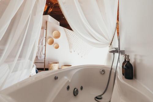 a white bath tub in a bathroom with white curtains at Joy Beach House in São Pedro de Moel
