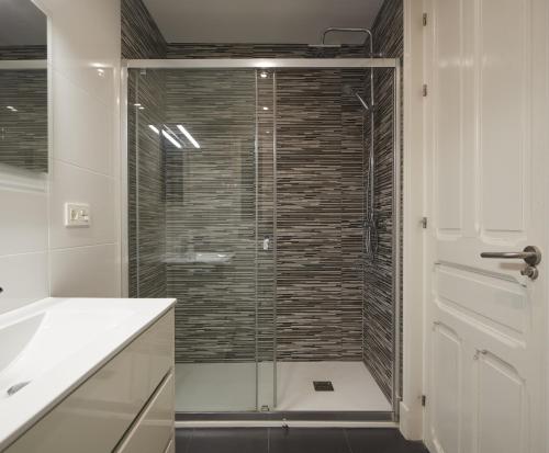 La salle de bains est pourvue d'une douche avec une porte en verre. dans l'établissement Pausoka - Basque Stay, à Saint-Sébastien