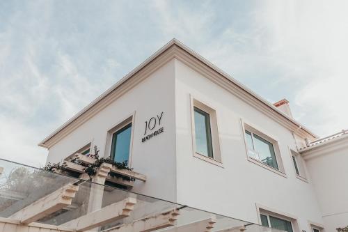 a white building with a joy sign on it at Joy Beach House in São Pedro de Moel