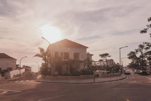 a house on a street with the sun in the sky at Joy Beach House in São Pedro de Moel