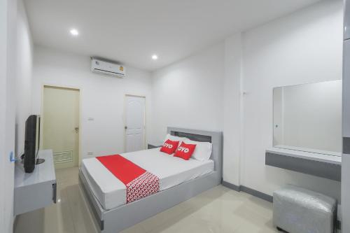 una camera bianca con letto con cuscini rossi di OYO 1159 K&k Apartment a Samutprakarn