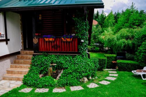 a garden with a red fence and green plants at Apartments Predah, Mijaila Radovica 13a in Zlatibor