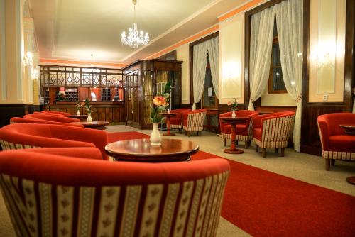 a waiting room with red chairs and tables and a lobby at Belvedere Spa & Kurhotel in Františkovy Lázně