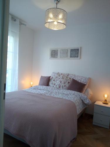 - une chambre blanche avec un lit et un lustre dans l'établissement Welcome au Dazzling Stay, à Serris