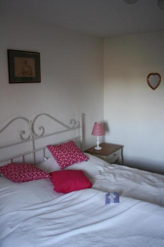 a white bed with two red pillows on it at Ferienwohnung Jacobshof in Oberstedem