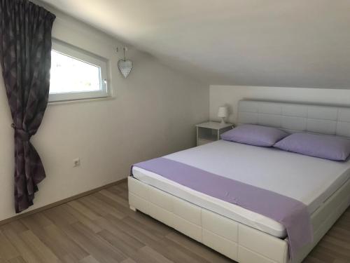 a bedroom with a bed with purple pillows and a window at Apartment Purple Loft in Hvar