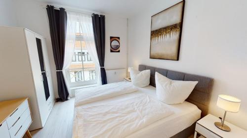 1 dormitorio con cama blanca y ventana en Lieblingsapartment mit 2 Schlafzimmern - Nördliche Altstadt in Rostock, en Rostock