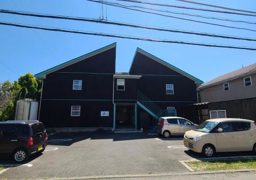 a black building with cars parked in a parking lot at Bluebird Hotel in Fujikawaguchiko