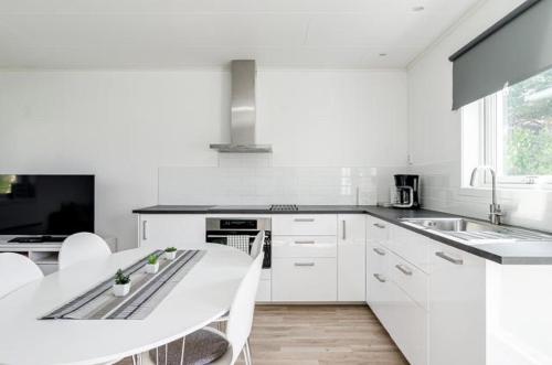a kitchen with white cabinets and a white table and chairs at Great Stay Guest House Sandviken in Sandviken