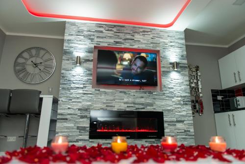 a living room with a stone fireplace with a tv at Aphrodite Suites in Bradford