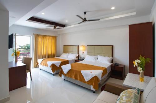 a hotel room with two beds and a couch at Hotel Viswa Grand in Kanyakumari