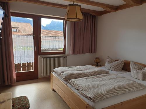 1 dormitorio con 2 camas y ventana grande en Gästehaus Stefanie, en Schwangau