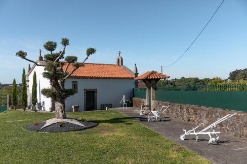 a house with a tree and chairs in a yard at A Casinha in Vila Nova de Famalicão