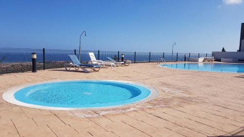 a swimming pool with two lounge chairs next to the ocean at Casa Roca in Caleta De Fuste