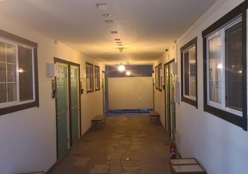 an empty hallway with green doors and windows at Bluebird Hotel in Fujikawaguchiko