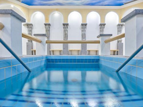 an indoor swimming pool with blue tiles and columns at Parkhotel Bad Griesbach in Bad Griesbach
